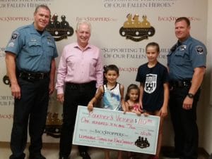 Roderick and Victoria present their check for $110.00 with big sister Anna Rose to The BackStoppers Executive Director Chief Ron Battelle and Frontenac Police Officers