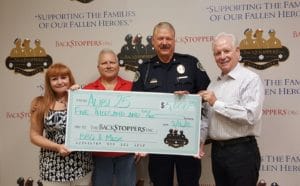 Alibi 25 General Manager Denise Gestring and Bill [Last Name] present a check for $5,000 to Ellisville Police Chief Tom Felgate and The BackStoppers Executive Director Chief Ron Battelle